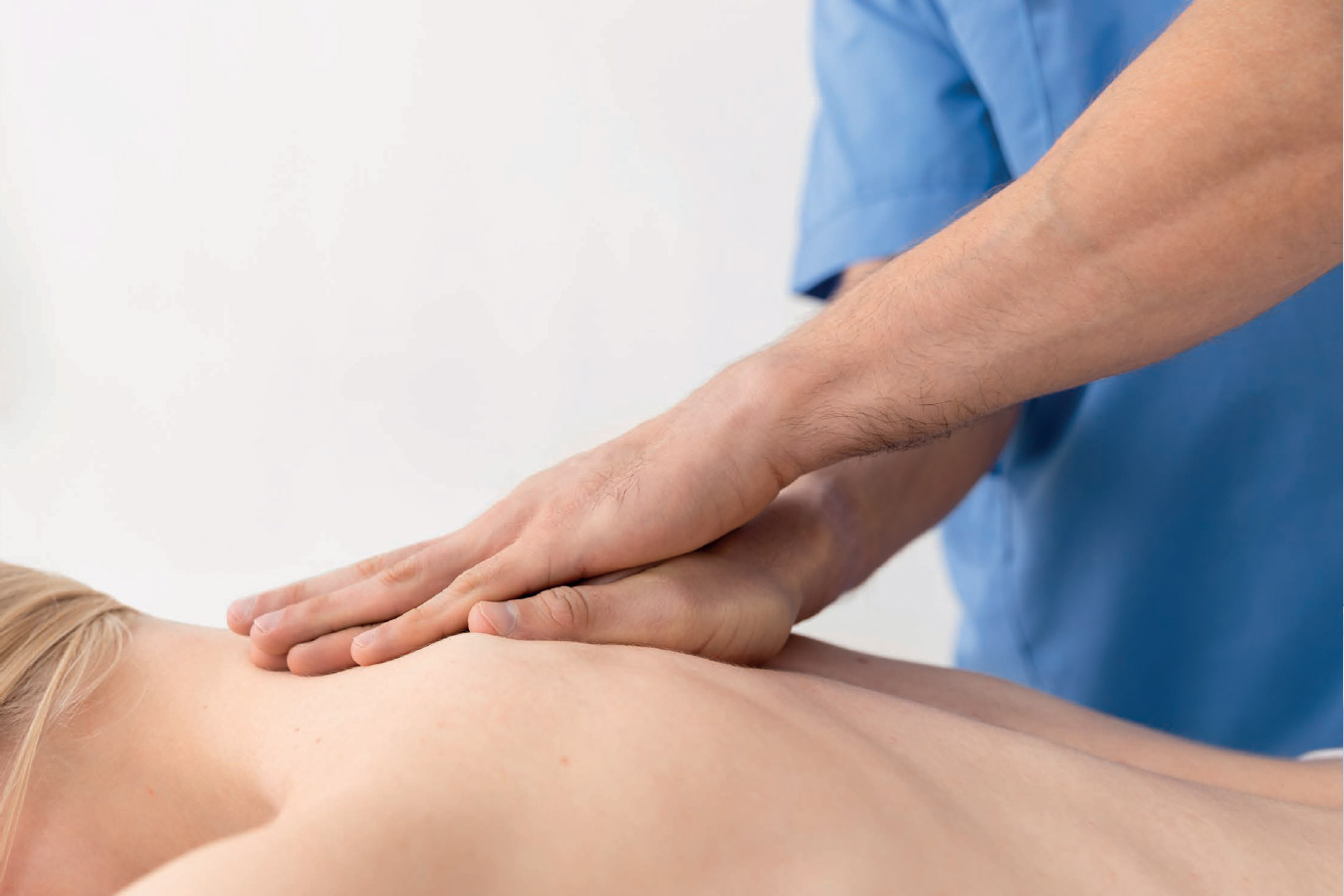 Donna sdraiata su un lettino in uno studio di fisioterapia mentre riceve un massaggio alla schiena da un professionista