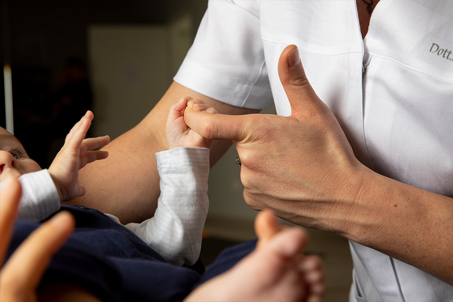 Una donna tiene delicatamente la mani di un neonato